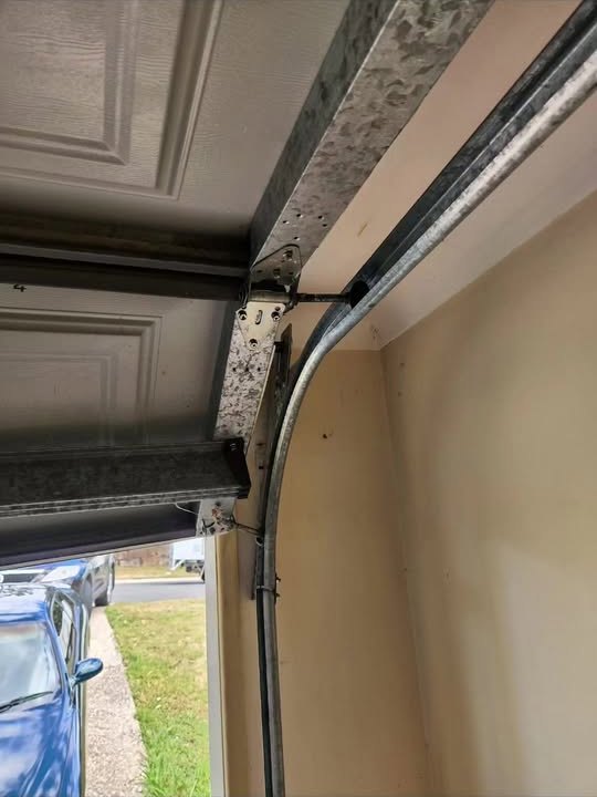 Close up of garage door track and rollers during a repair